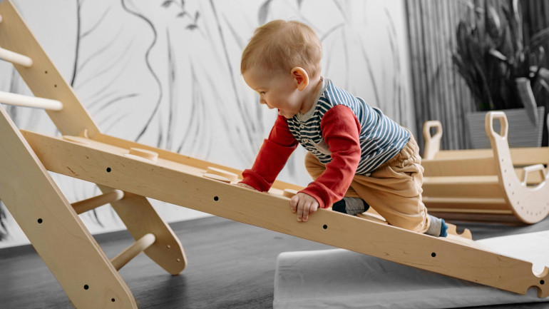 Enfant qui joue avec des jouets Pikler